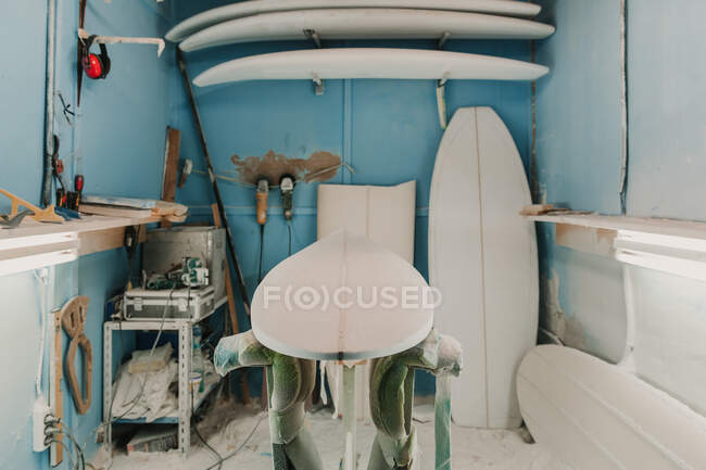 Local de trabalho com pranchas de surf de madeira perto da prateleira com aviões de carpinteiro — Fotografia de Stock