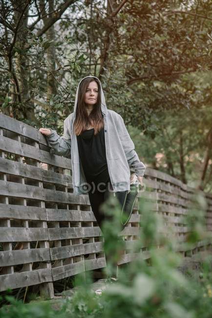 Жінка розтягується біля дерев'яного паркану в парку — стокове фото