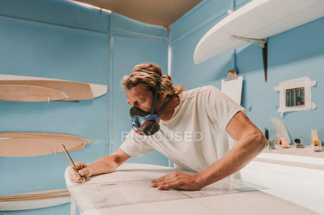 Seitenansicht des Mannes in Atemluft mit Bleistift und Surfbrett am Arbeitsplatz — Stockfoto