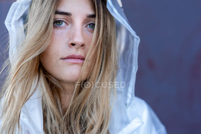 Portrait of charming stylish woman in raincoat sitting near wall — Stock Photo