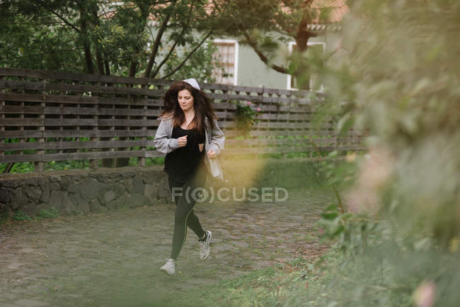 Женщина в спортивной одежде бежит по тропинке в сельской местности — стоковое фото