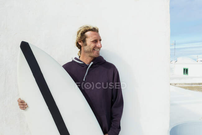 Uomo sorridente in piedi con tavola da surf — Foto stock