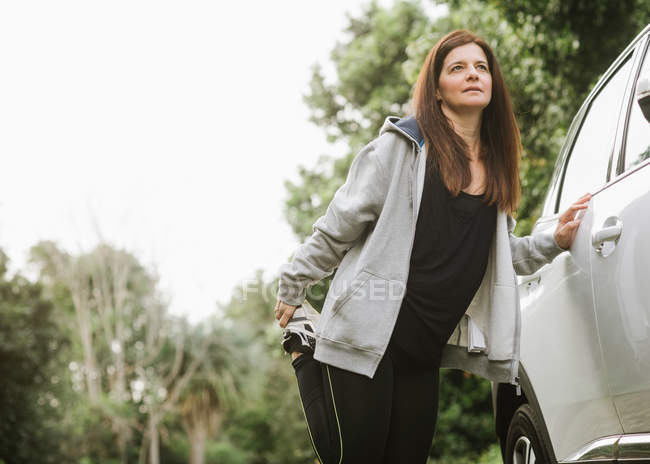 Mulher em sportswear esticando perto de carro no parque — Fotografia de Stock
