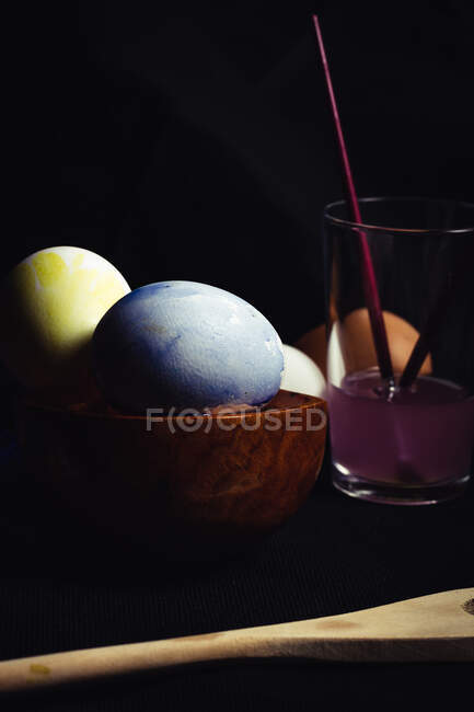 Vetro con acqua colorata vicino alle uova dipinte — Foto stock