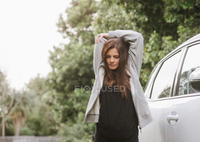 Frau in Sportkleidung streckt sich in Parkhaus neben Auto — Stockfoto