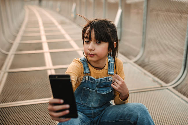 Lustiges Mädchen macht Selfie mit Smartphone auf Metallsteg — Stockfoto