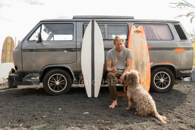 Mann steht neben Surfbrett und Transporter — Stockfoto