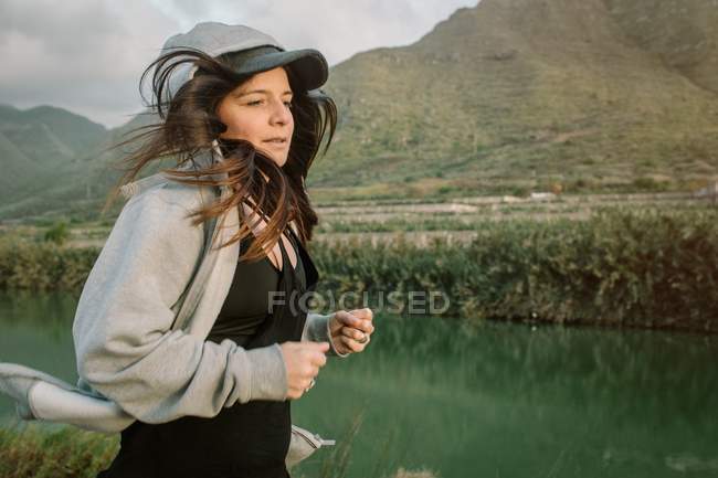 Frau in Sportkleidung läuft in der Natur am See und in den Bergen — Stockfoto