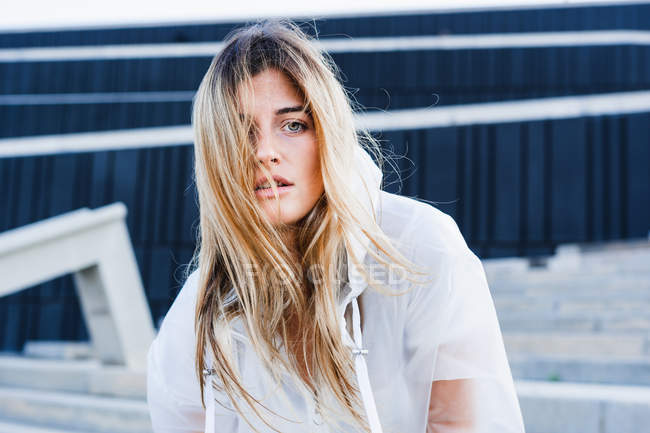 Чуттєва молода жінка в плащі позує на вулиці — стокове фото