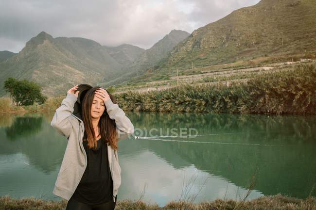 Усталая женщина отдыхает после бега на природе возле озера и гор — стоковое фото