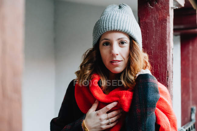 Woman in winter wear with hand on chest looking at camera and standing near building — Stock Photo