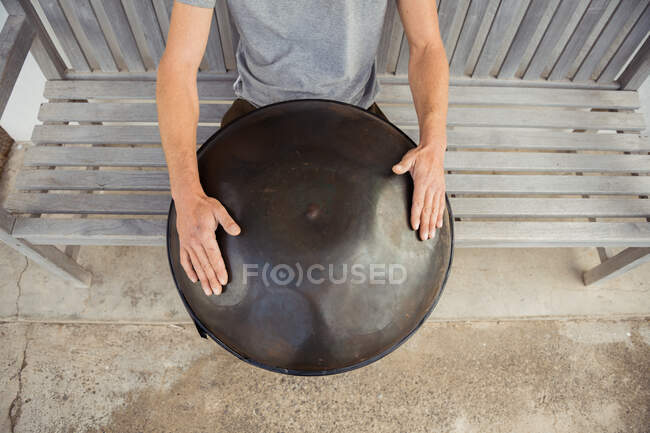 Homem loiro sentado no banco com tambor grande mão — Fotografia de Stock