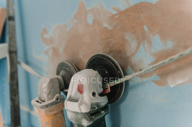 Closeup dirty grinders hanging on twist near blue wall with brown blots — Stock Photo