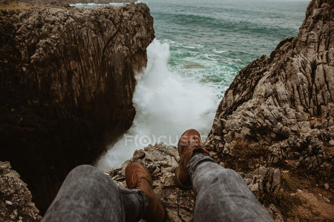 Ernte Beine des Menschen sitzen auf Stein in der Nähe stürmischer See in Bufones de pria, Asturien, Spanien — Stockfoto