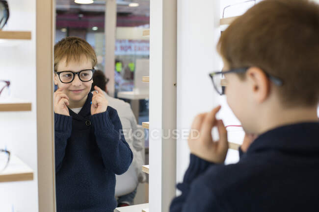 Милый мальчик примеряет очки в магазине очков. — стоковое фото
