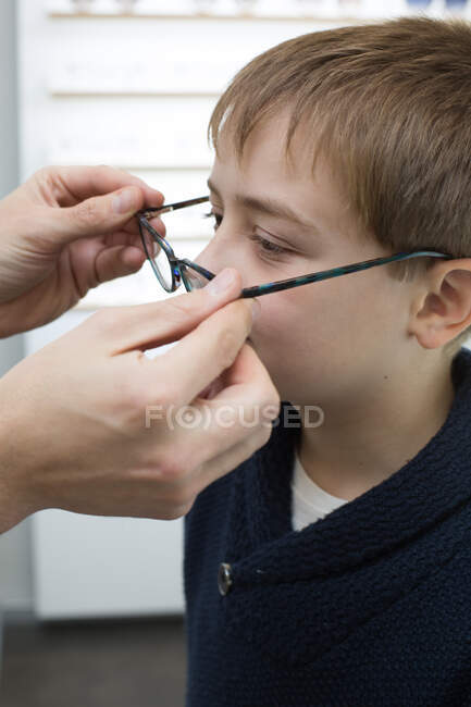 Rapaz bonito experimentando óculos em uma loja de óculos — Fotografia de Stock