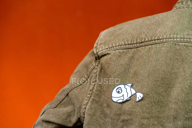 Vue arrière du gars avec silhouette en papier pour avril imbéciles jour sur veste en jean sur fond orange — Photo de stock