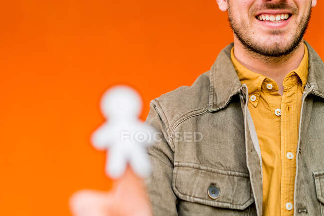Happy guy showing paper silhouette for April fools day on orange blurred background — Foto stock