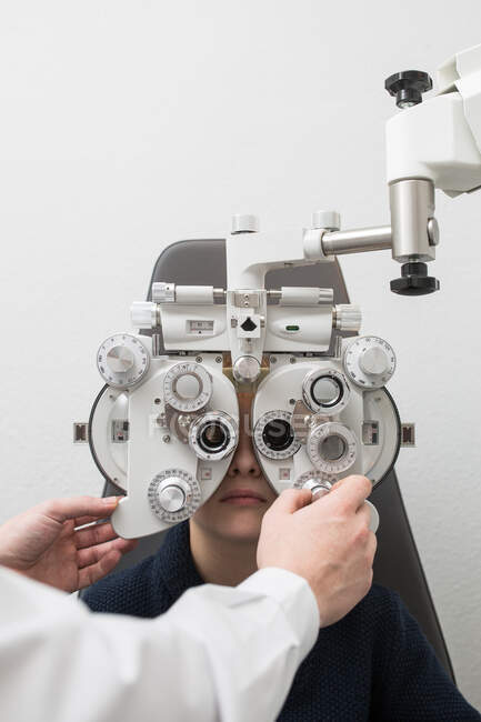 Opticien testant les yeux d'un garçon avec des dispositifs d'optométrie — Photo de stock