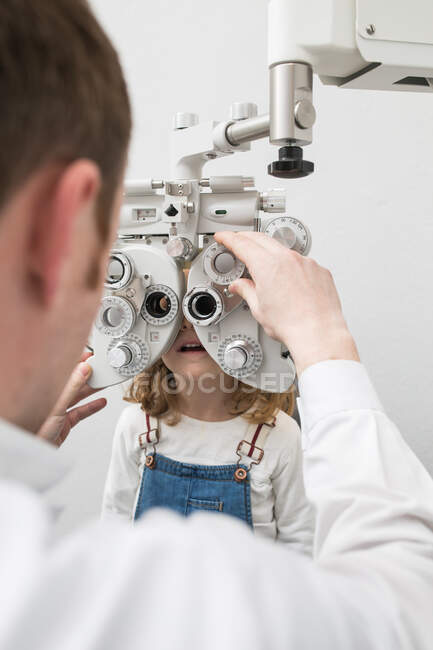 Ottico testare gli occhi di una ragazza con dispositivi di optometria — Foto stock