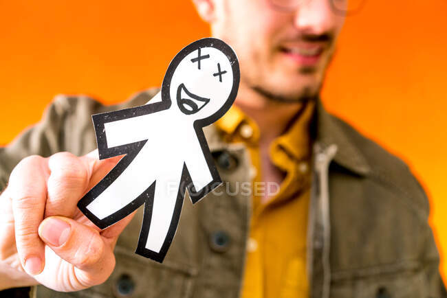 Щасливий хлопець показує паперовий силует для квітня день дурнів на помаранчевому розмитому фоні — стокове фото