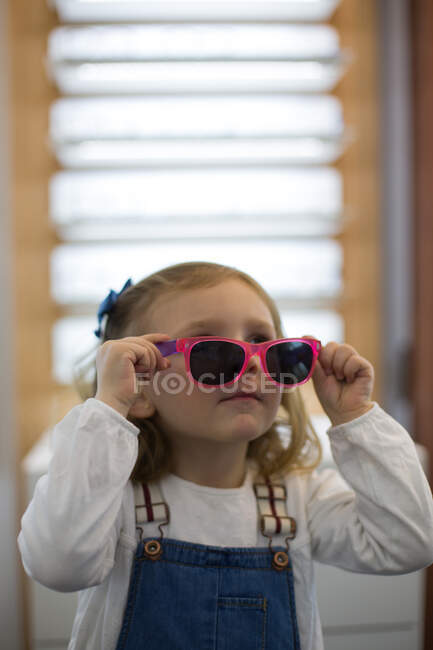 Мила дівчинка пробує окуляри в магазині окулярів. — стокове фото