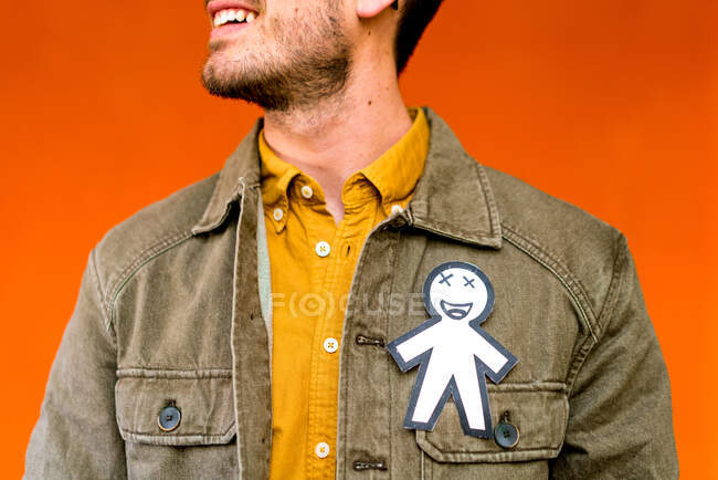 Crop happy guy with paper silhouette for April fools day on jean jacket on orange background — Stock Photo