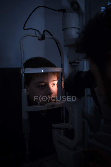 Optician testing a boy's eyes with optometry devices — Stock Photo