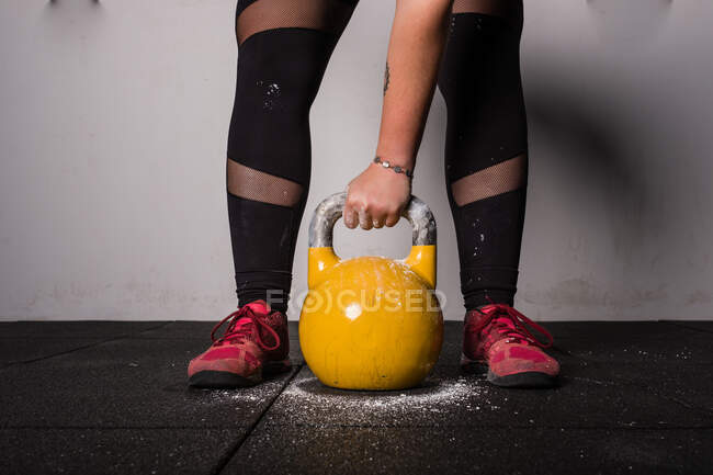 Athletic young concentrated woman in sportswear upping kettlebell in gym — Stock Photo