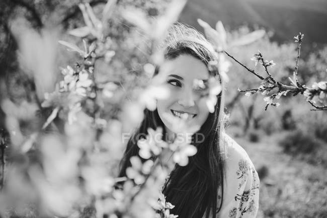 Twigs of blooming fruit tree cheerful lady looking away in garden — Stock Photo