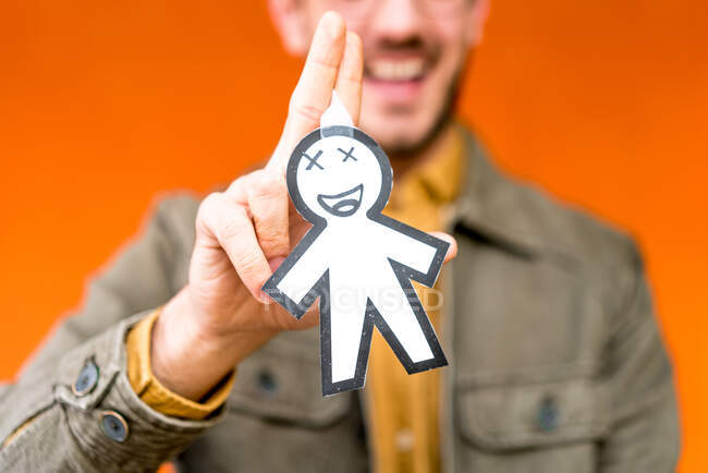 Счастливый парень, изображающий бумажный силуэт апрельского дня дураков на оранжевом размытом фоне — стоковое фото
