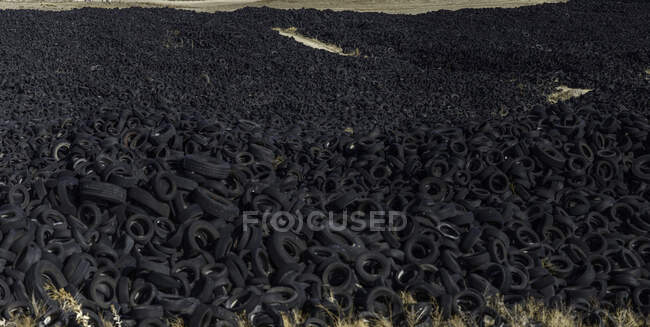 Enorme mucchio di vecchi pneumatici auto tra prato — Foto stock