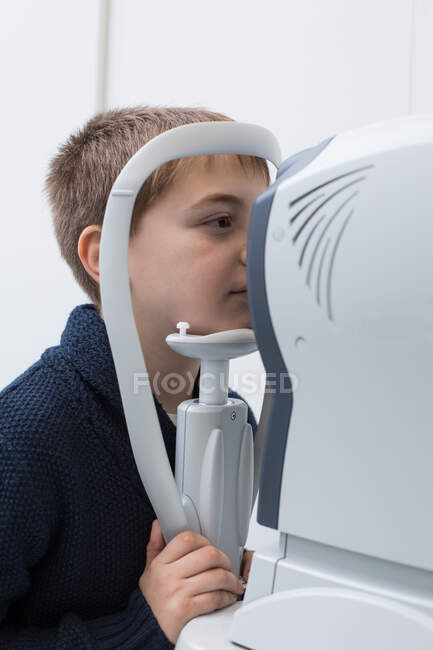 Ottico testare gli occhi di un ragazzo con dispositivi di optometria — Foto stock