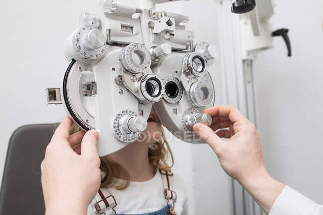 Optician testing a girl's eyes with optometry devices — Stock Photo