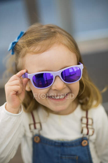 Cute young girl trying on glasses in an eyewear store — Stock Photo