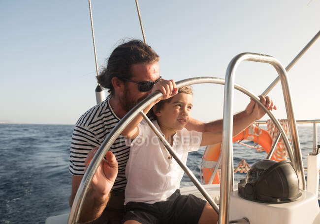 Vater und Sohn treiben bei schönem Wetter auf teurem Boot auf dem Meer und blauem Himmel — Stockfoto