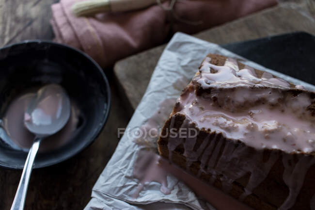 Cucchiaio versando condimento sulla torta fresca gustosa arancia posto sul tovagliolo vicino asciugamano e pennello su sfondo nero — Foto stock