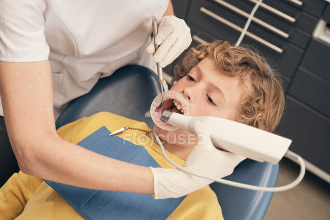 Hände des Arztes bei der Untersuchung der Zähne des kleinen Jungen während der Arbeit in der Zahnarztpraxis — Stockfoto