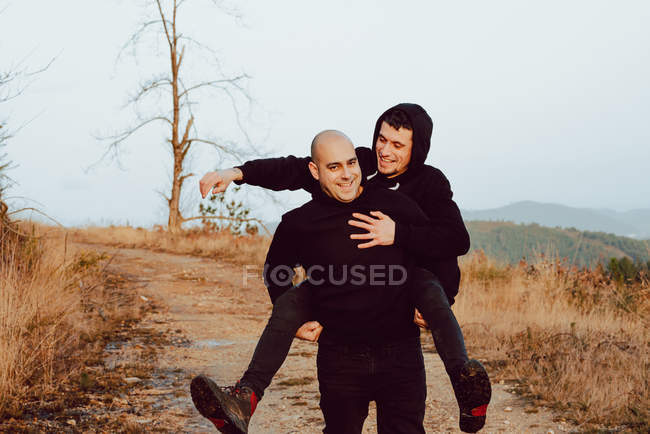 Glückliches homosexuelles Paar hat Spaß auf dem Weg zwischen Pflanzen in den Bergen — Stockfoto