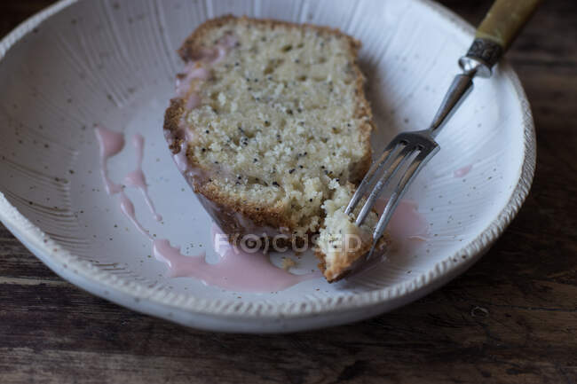 De cima fatia de bolo de laranja saboroso fresco com sementes de papoula e cobertura em prato perto de garfo em fundo de madeira — Fotografia de Stock