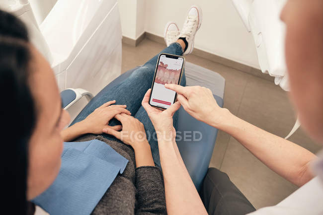 Dentiste démontrant smartphone avec balayage des dents au patient en clinique — Photo de stock
