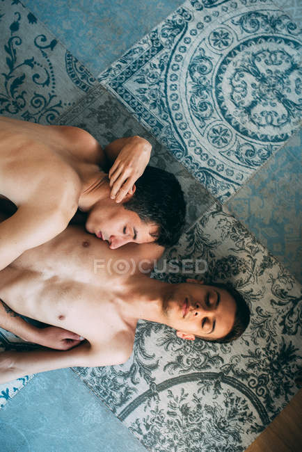 Apasionado sexual desnudo gay pareja en un íntimo momento acostado en un alfombra en casa - foto de stock