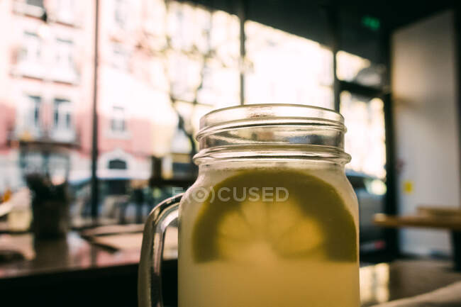 Tazas de vidrio con deliciosa bebida fresca de limón sobre fondo borroso - foto de stock