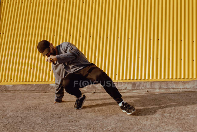 Guy performing dancing near wall of modern building on city street — Stock Photo