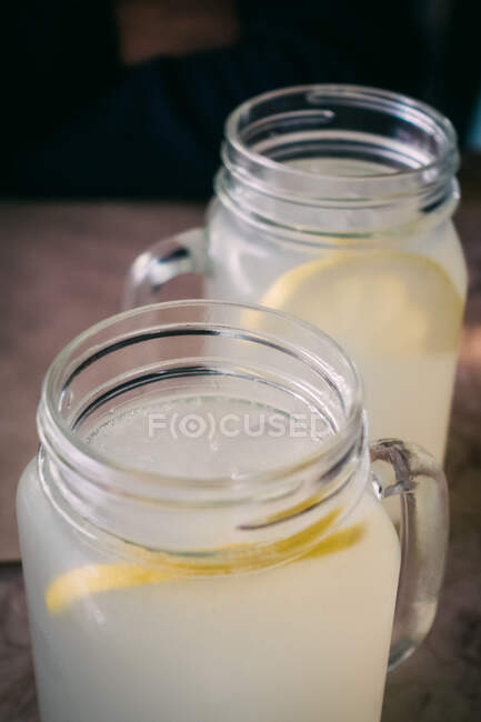 D'en haut tasses en verre gros plan avec délicieuse boisson au citron frais sur fond flou — Photo de stock