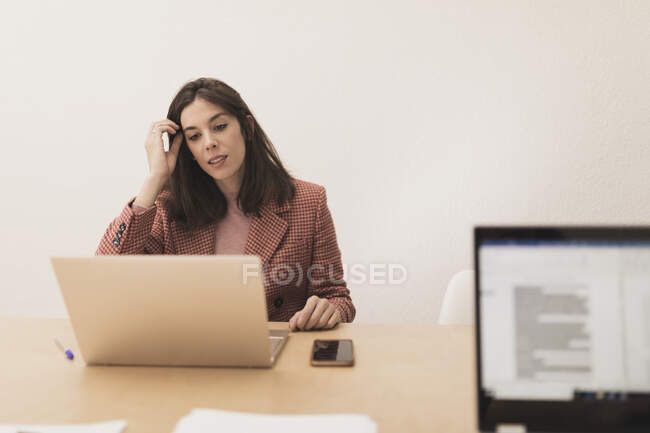 Concentré jeunes femmes naviguant sur les ordinateurs portables et assis à la table dans le bureau — Photo de stock