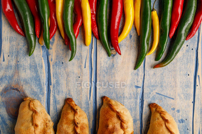 Set of homemade patties and fresh green and red chili peppers on grey wooden table — Stock Photo
