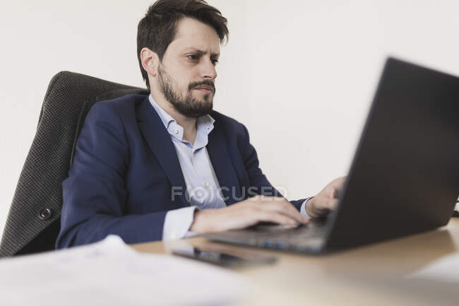 Concentré jeune mâle navigation sur ordinateur portable à la table dans le bureau — Photo de stock