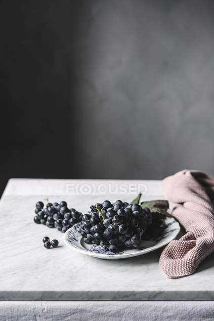 Ramo de uvas frescas en plato sobre mesa - foto de stock