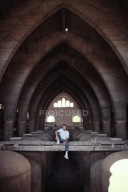 Man sitting on bridge inside old building arches — Stock Photo